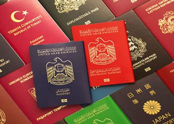 Blue and red biometric passports of United Arab Emirates on background of various documents of many countries of the world