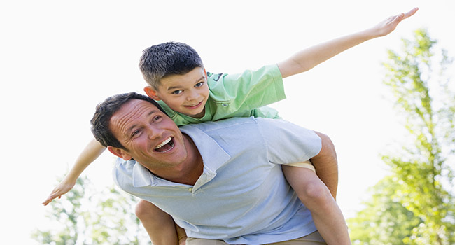 Woman giving son piggy back in park