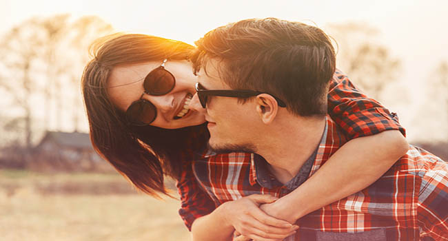 Smiling hipster couple in love woman embraces a man in sunny day