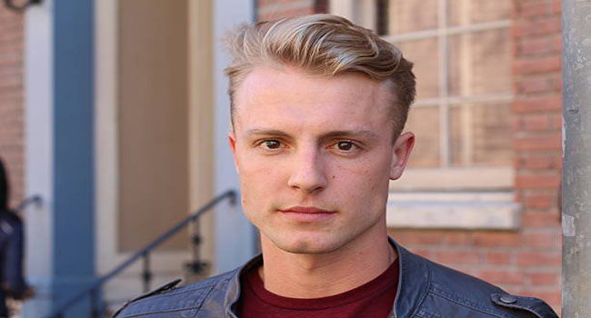 Close portrait of handsome adult blonde man, with blured urban classic background.