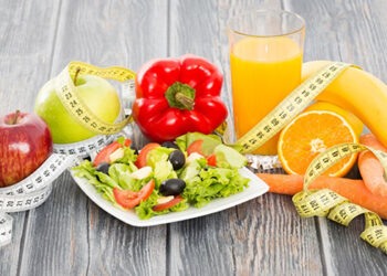 Fitness salad and measuring tape on wooden table.