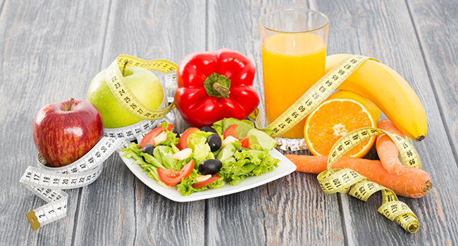 Fitness salad and measuring tape on wooden table.