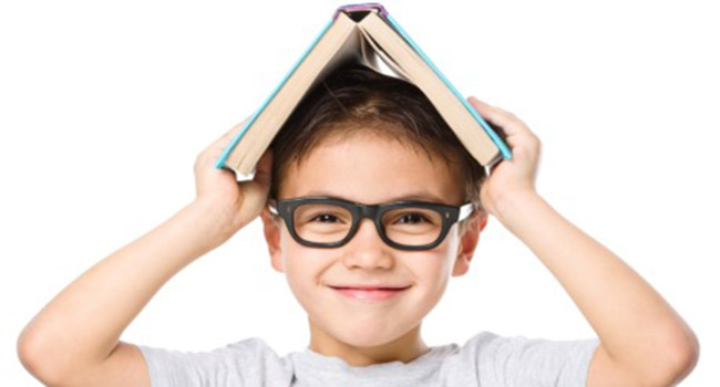 Cute little child plays with book while wearing glasses, isolated over white